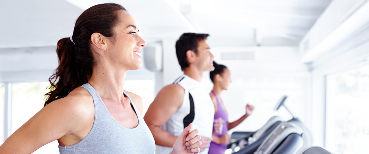 3 people running on treadmills in a gym.
