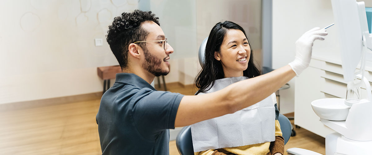 Dental professional reviewing digital dental images with a patient in a modern dental office. The image represents specialty healthcare services, preventive dental care, oral health education, treatment planning, and patient-provider collaboration using advanced dental technology.