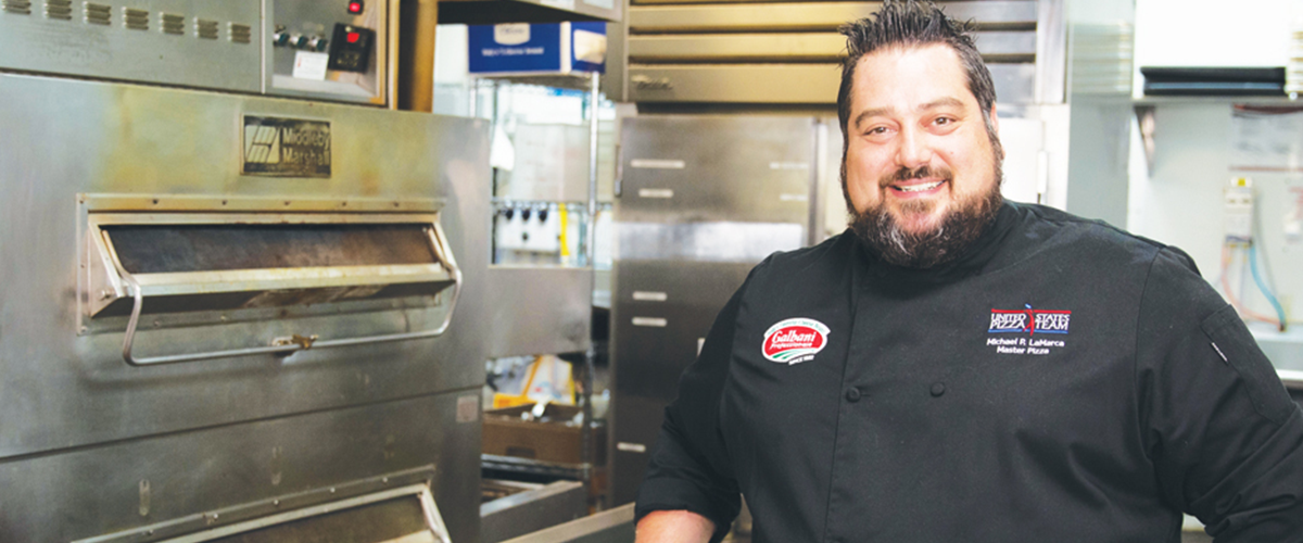 Master Pizza owner posing in a kitchen.