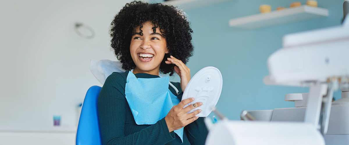Woman smiling, sitting in a chair at a dental office.