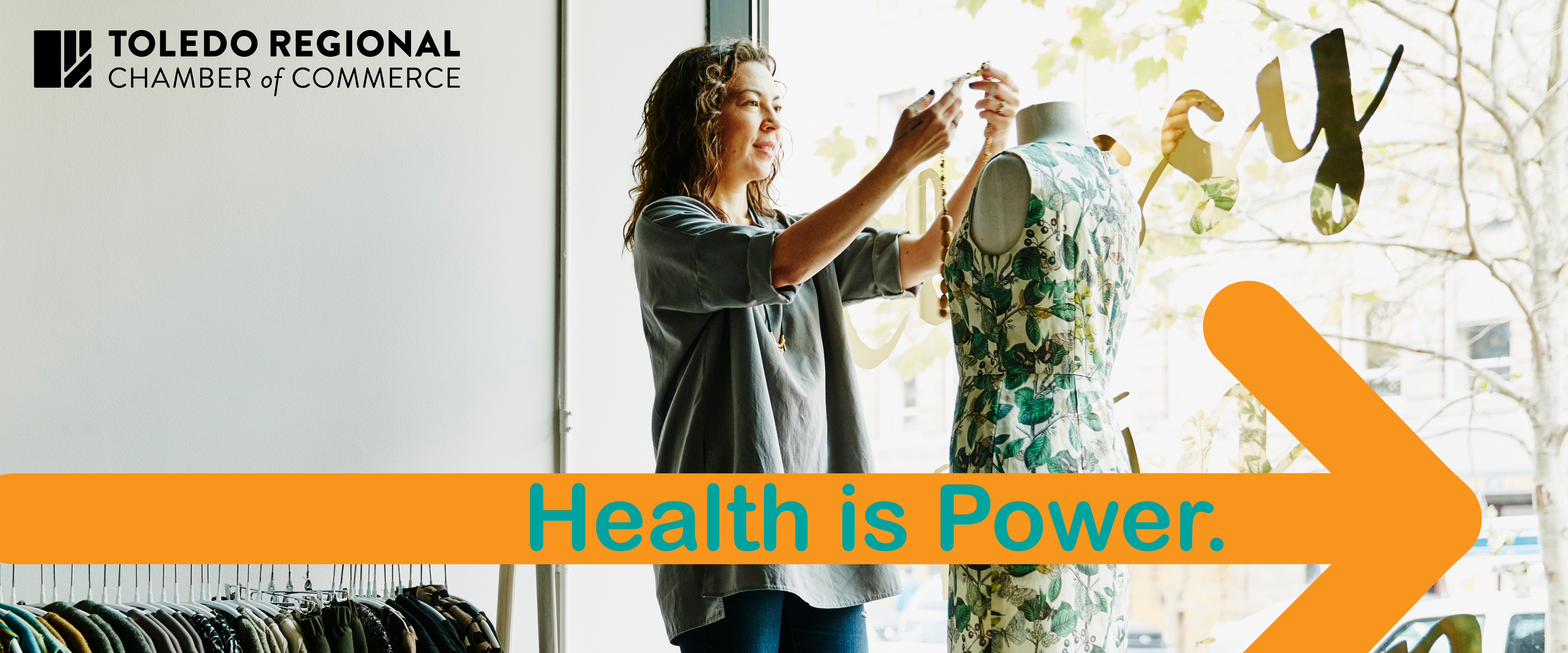 Woman dressing a mannequin in a clothing store with a graphic of an arrow that reads, "Health is Power."